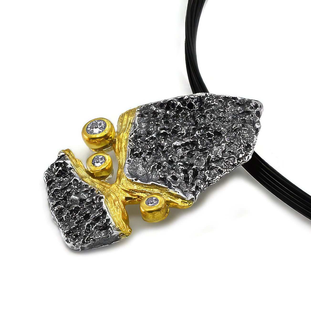 Schrägansicht des FELS Anhängers aus oxidiertem Silber mit Gold und weißen Saphiren am schwarzen Band.