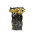 Frontalansicht des FELS Rings mit rauer Silberstruktur, goldener Fuge und zwei runden weißen Saphiren.