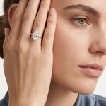 Ring W0689 aus 585er Gelbgold mit Labordiamant – an der Hand neben der Schläfe zur blaugrauen Bluse